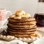 A stack of banana cottage cheese pancakes topped with sliced bananas.