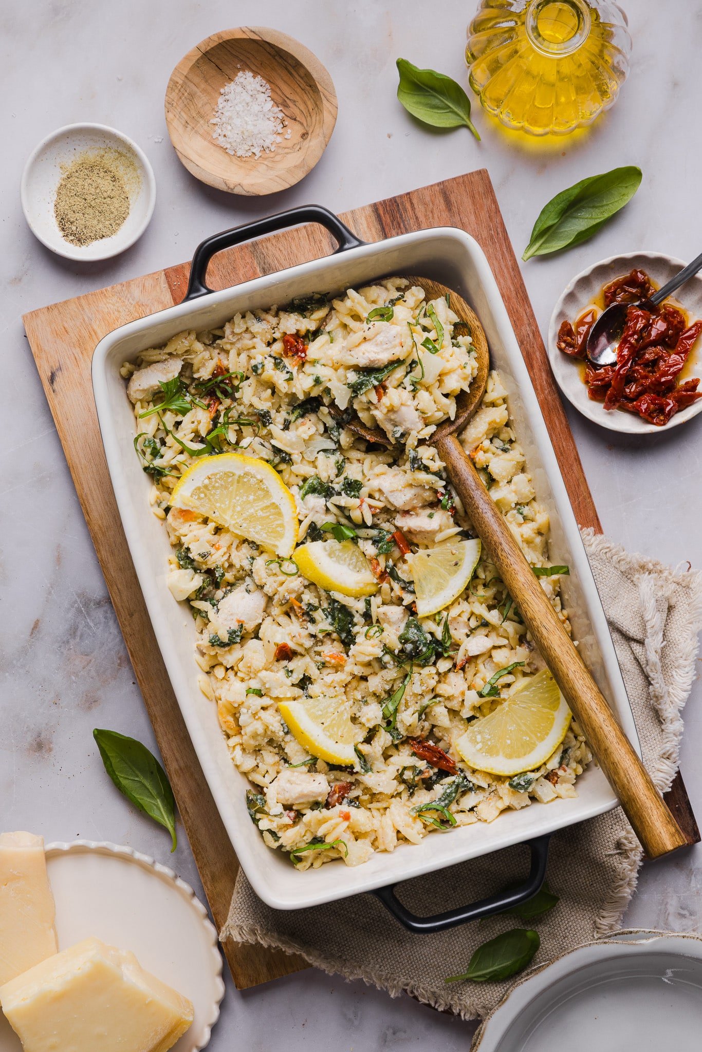 Chicken orzo bake garnished with basil and lemons.