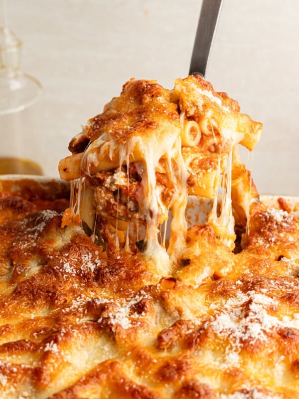 A hot scoop of high protein baked ziti being lifted from the baking dish with lots of cheese.