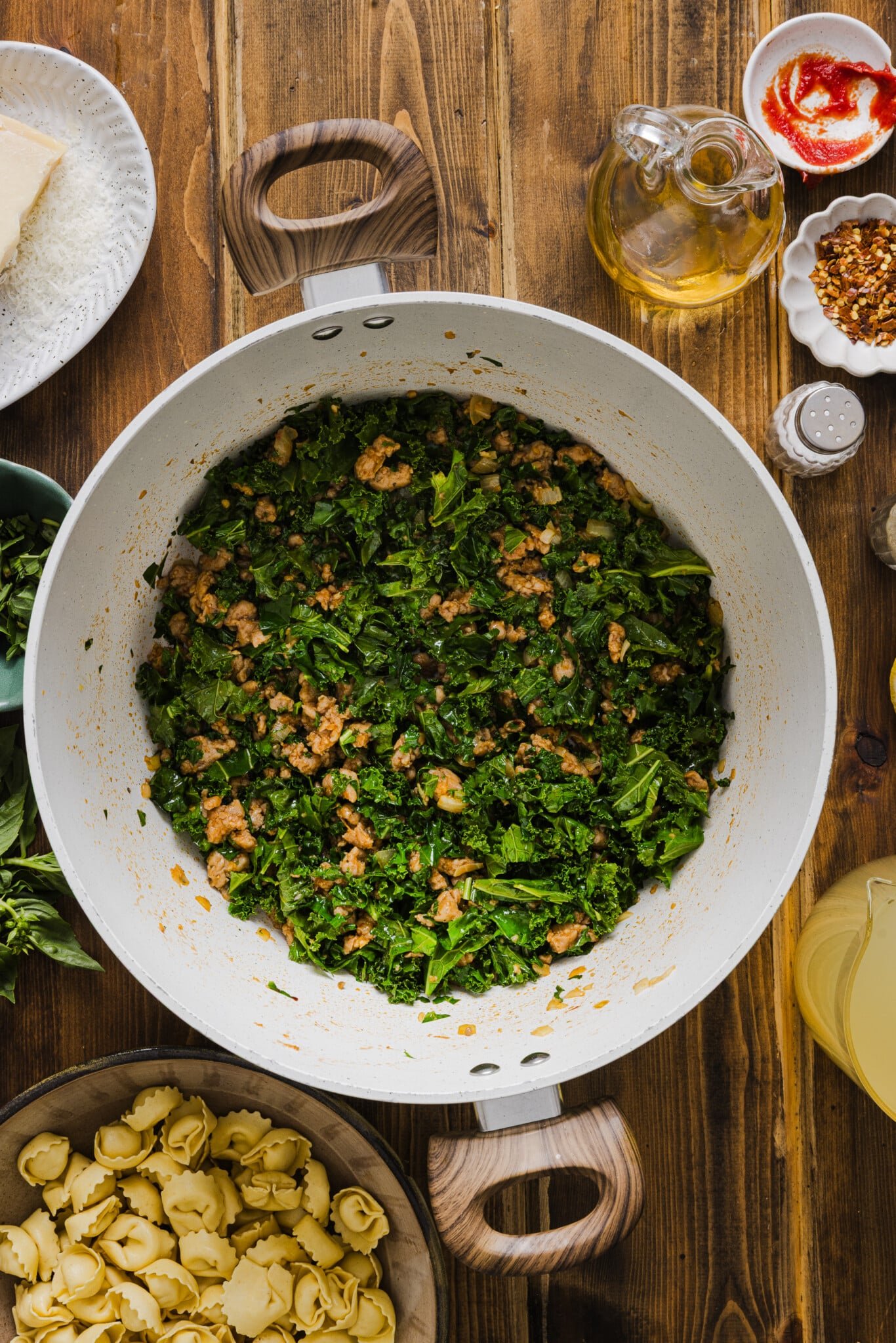A large soup pot with cooked turkey sausage and sautéed kale.