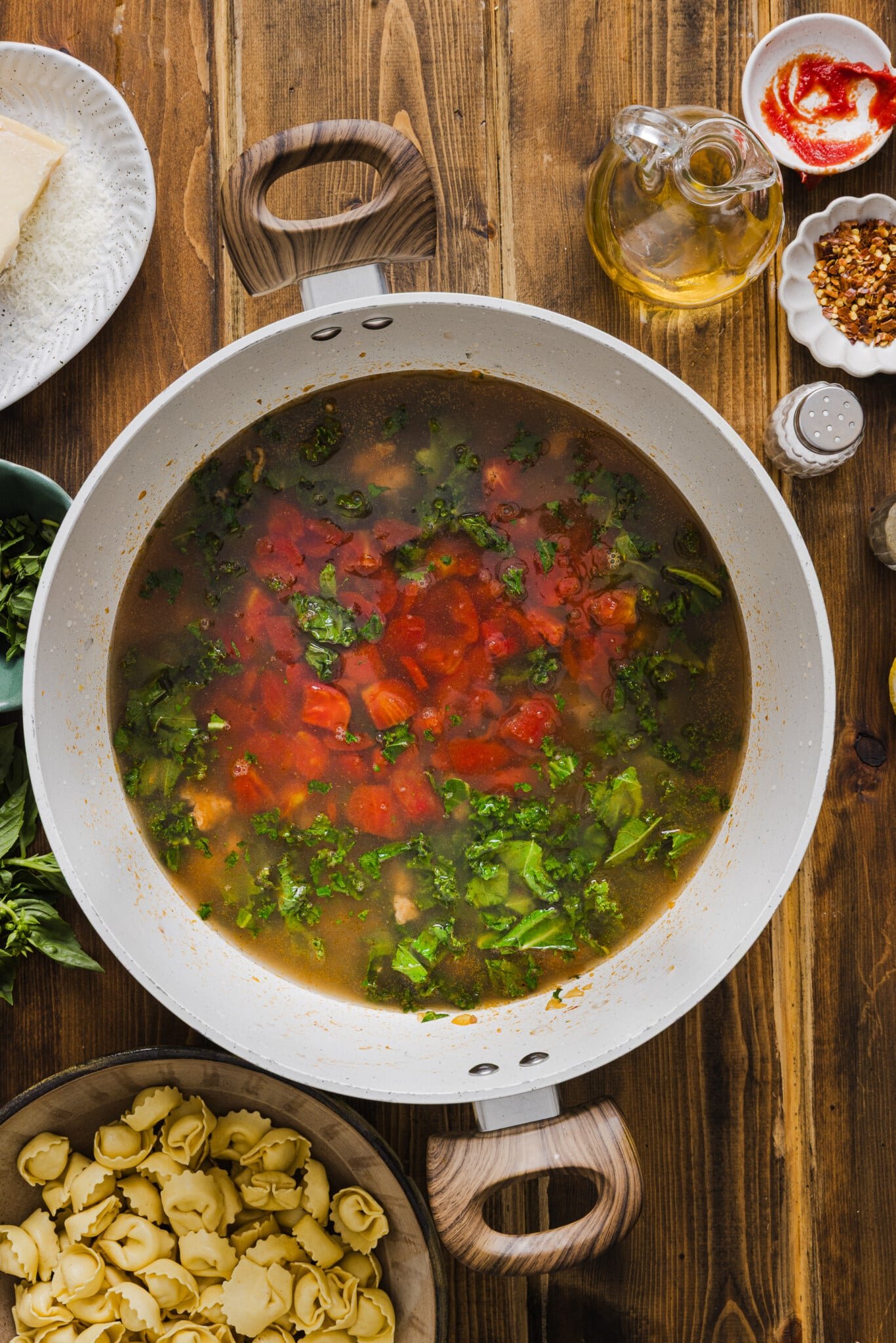 A large soup pot with broth and diced tomatoes added to cooked meat and onion mix.