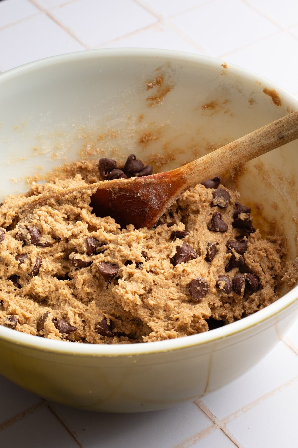 Oat flour cookie dough in a bowl with a wooden spoon.