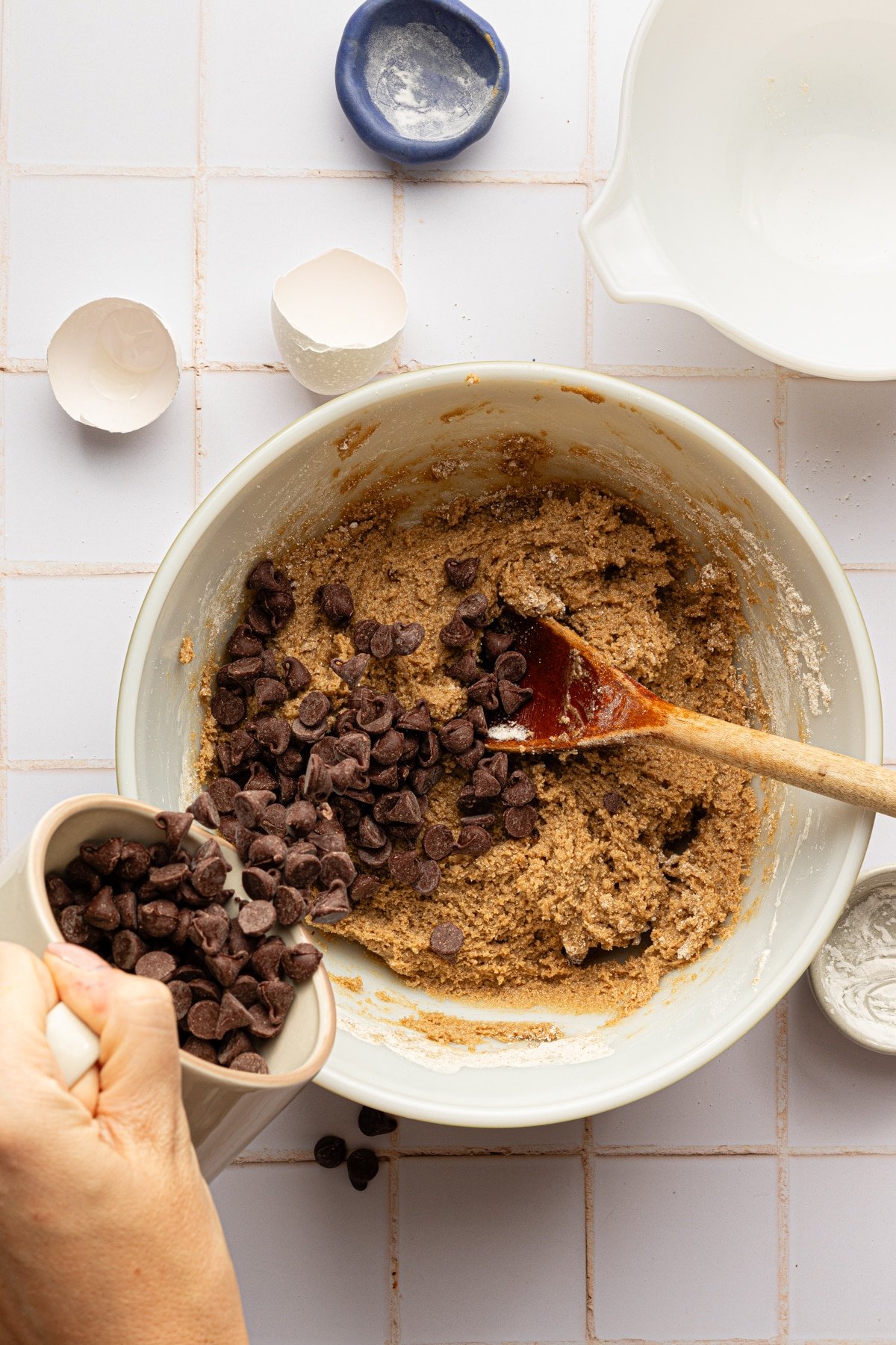 Chocolate chips being added to oat flour cookie batter.