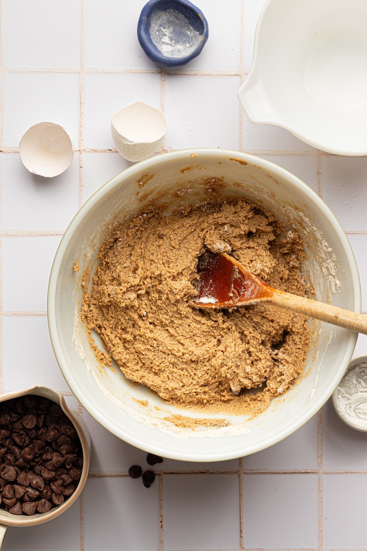 Oat flour dough for chocolate chip cookies mixed in a large white bowl.