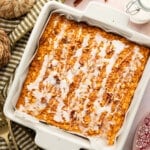 Protein pumpkin baked oats in a square white pan with a drizzle of powdered sugar glaze.
