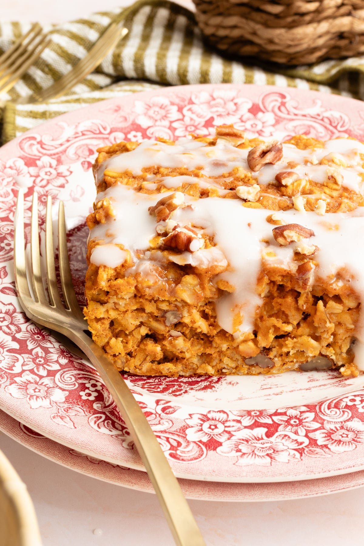 A square of protein pumpkin baked oats on a red and white toile plate with a fork.