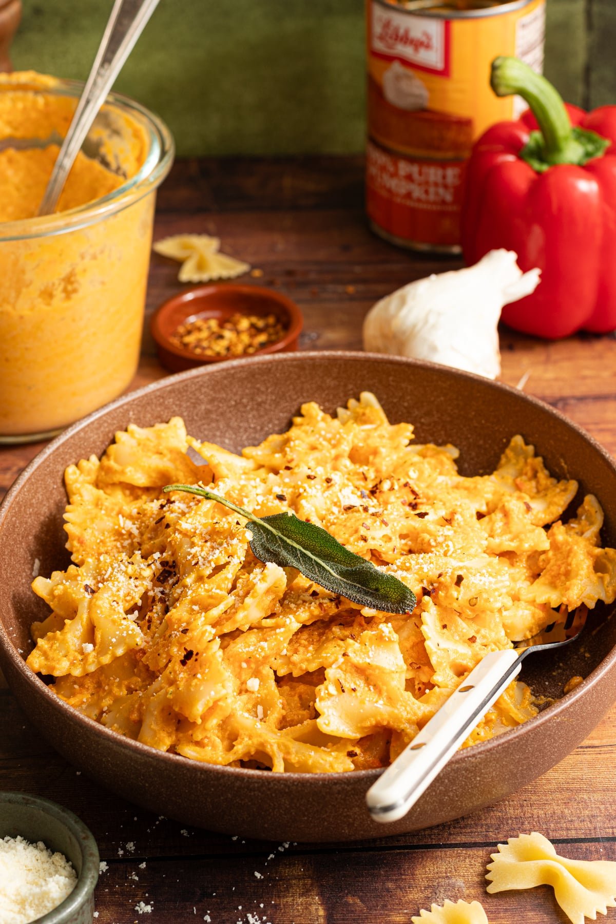 Protein pumpkin pasta sauce in a bowl garnished with parmesan cheese and sage.