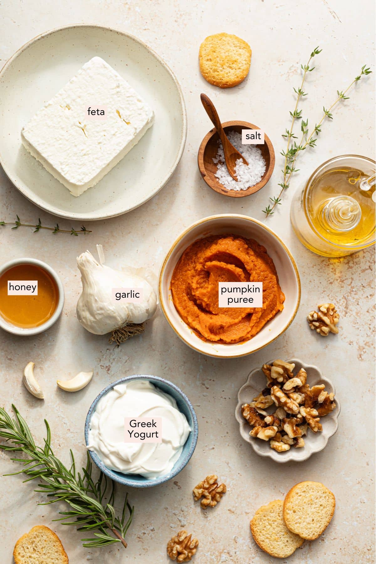 Individual ingredients to make pumpkin feta dip in small bowls on a marble countertop.