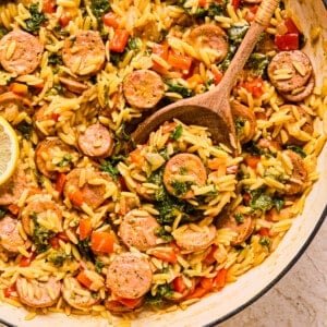 Chicken sausage orzo with kale and bell peppers in a skillet.