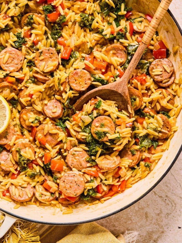 Chicken sausage orzo with kale and bell peppers in a skillet.