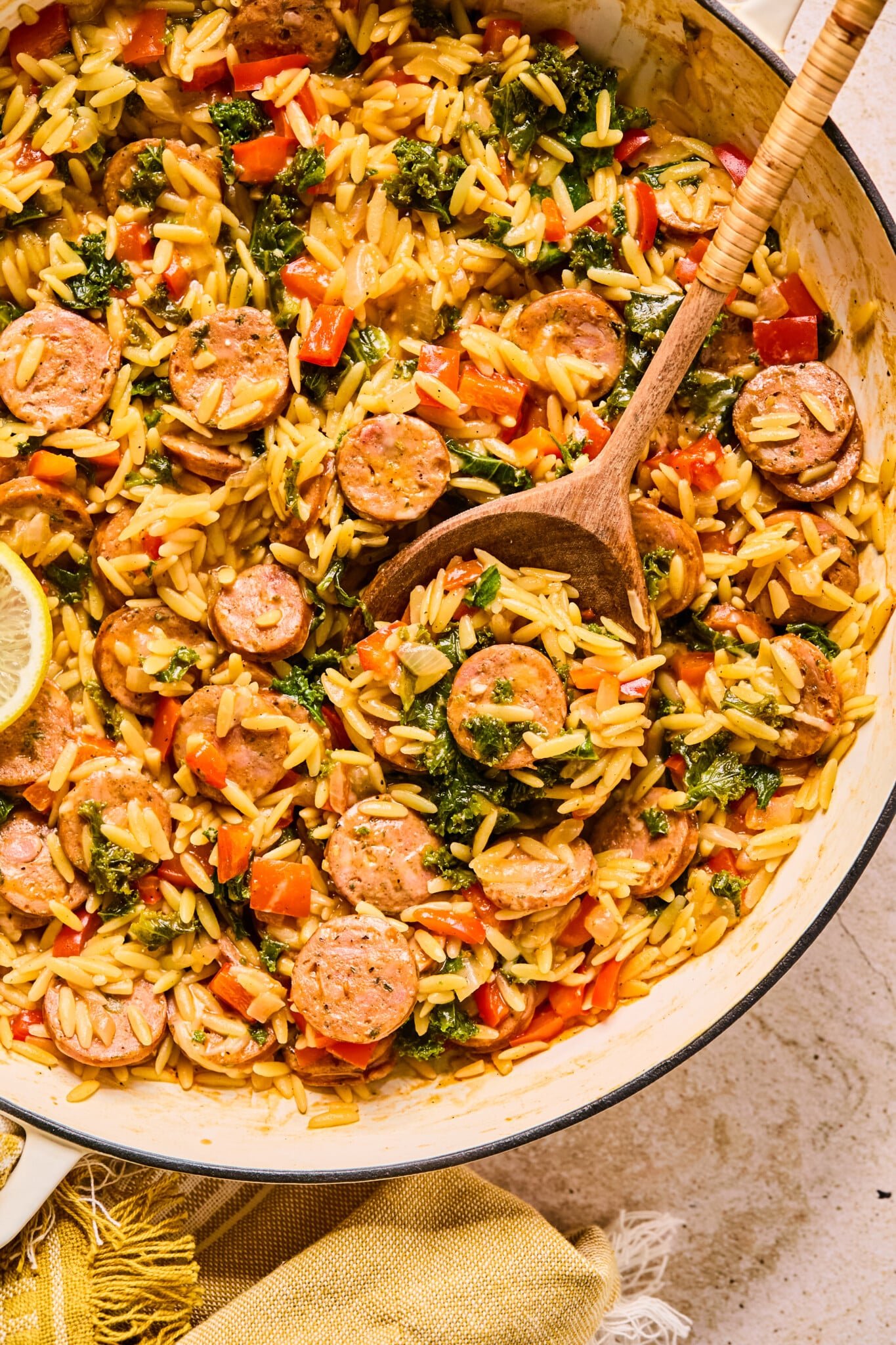 Chicken sausage orzo with kale and bell peppers in a skillet.
