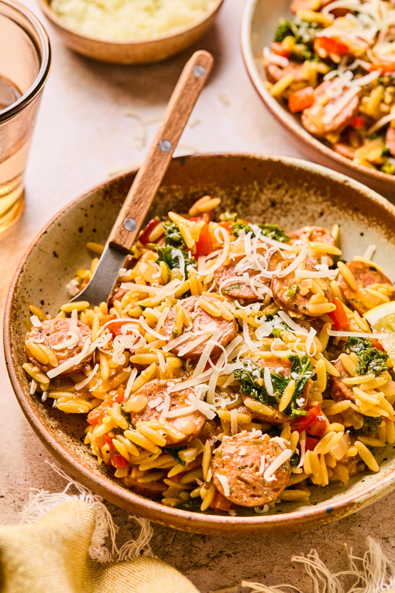Chicken sausage orzo in a bowl topped with parmesan cheese.
