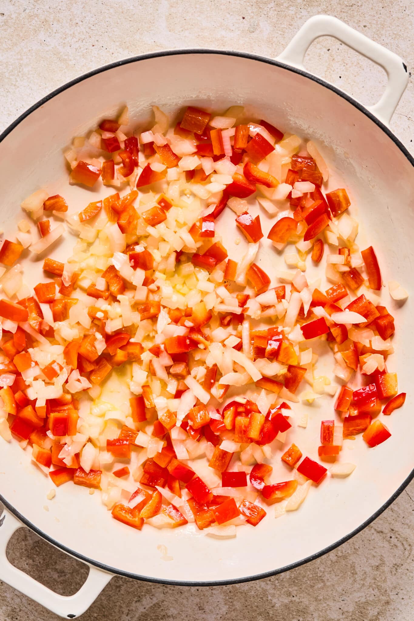 Onions peppers and garlic being sautéed in a skillet.