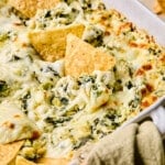 Baked cottage cheese spinach artichoke dip in a dish with tortilla chips.