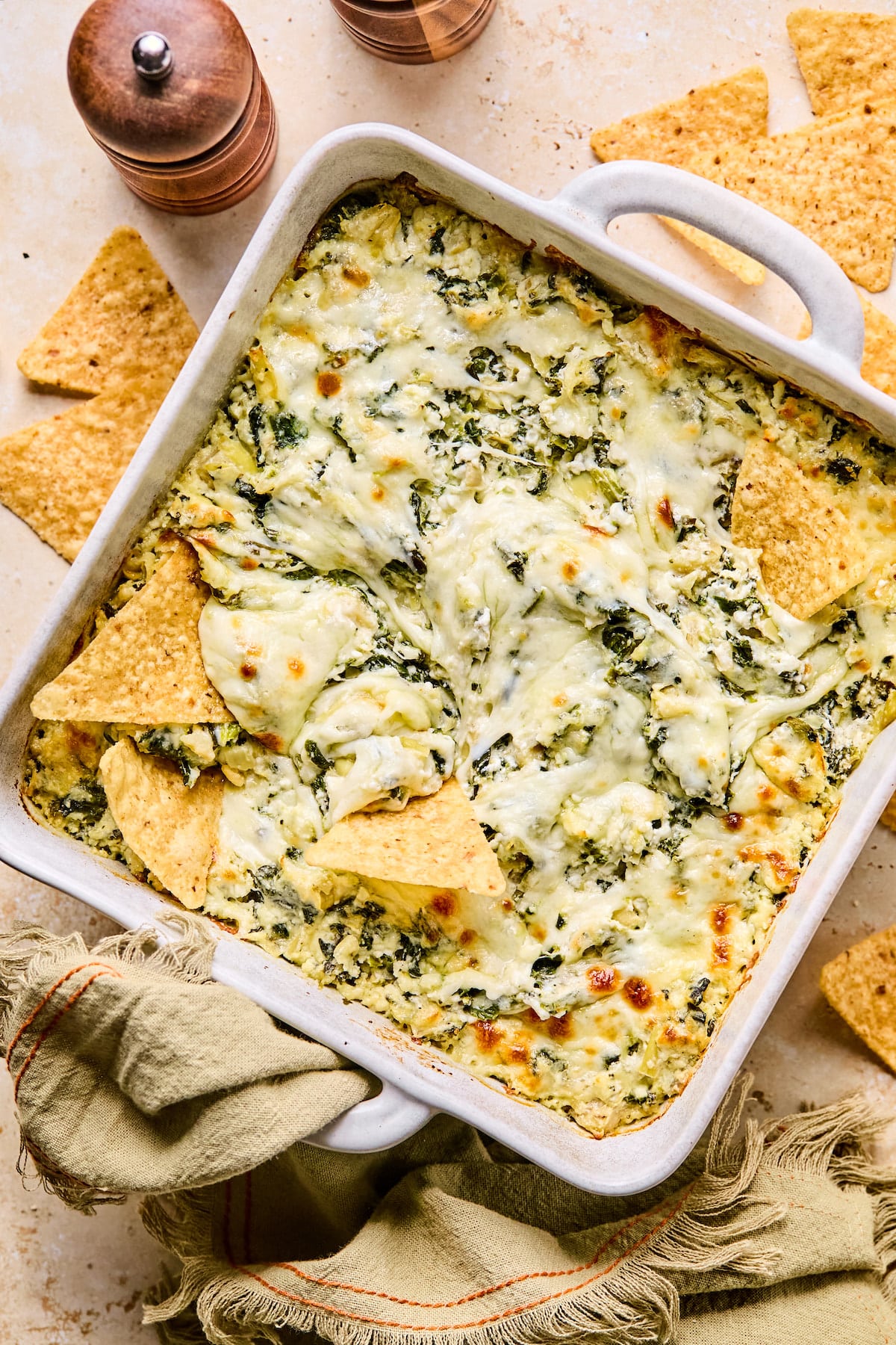 Baked cottage cheese spinach artichoke dip in a dish with tortilla chips.