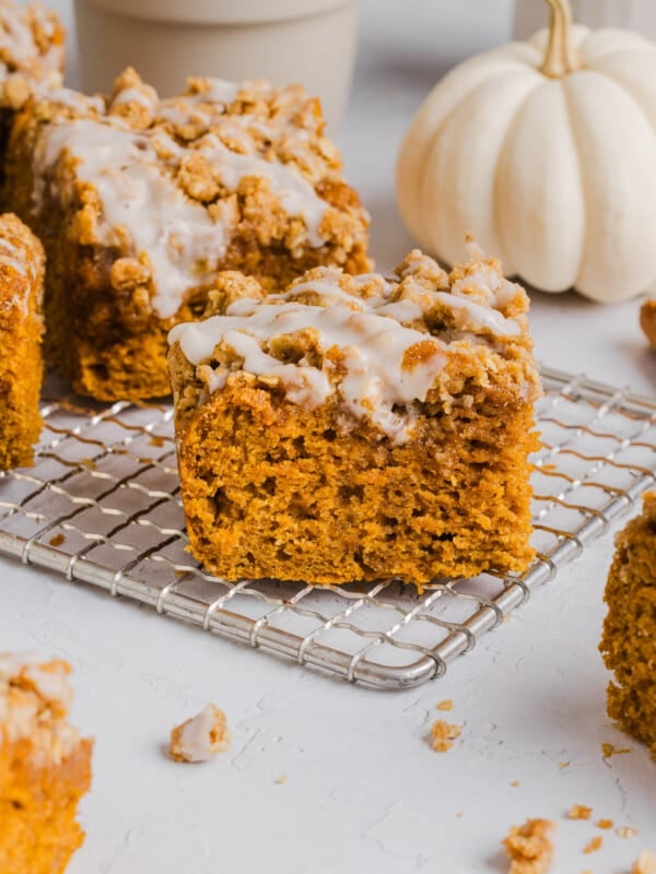 A slice of healthy pumpkin coffee cake on a baking rack with a glaze on top.