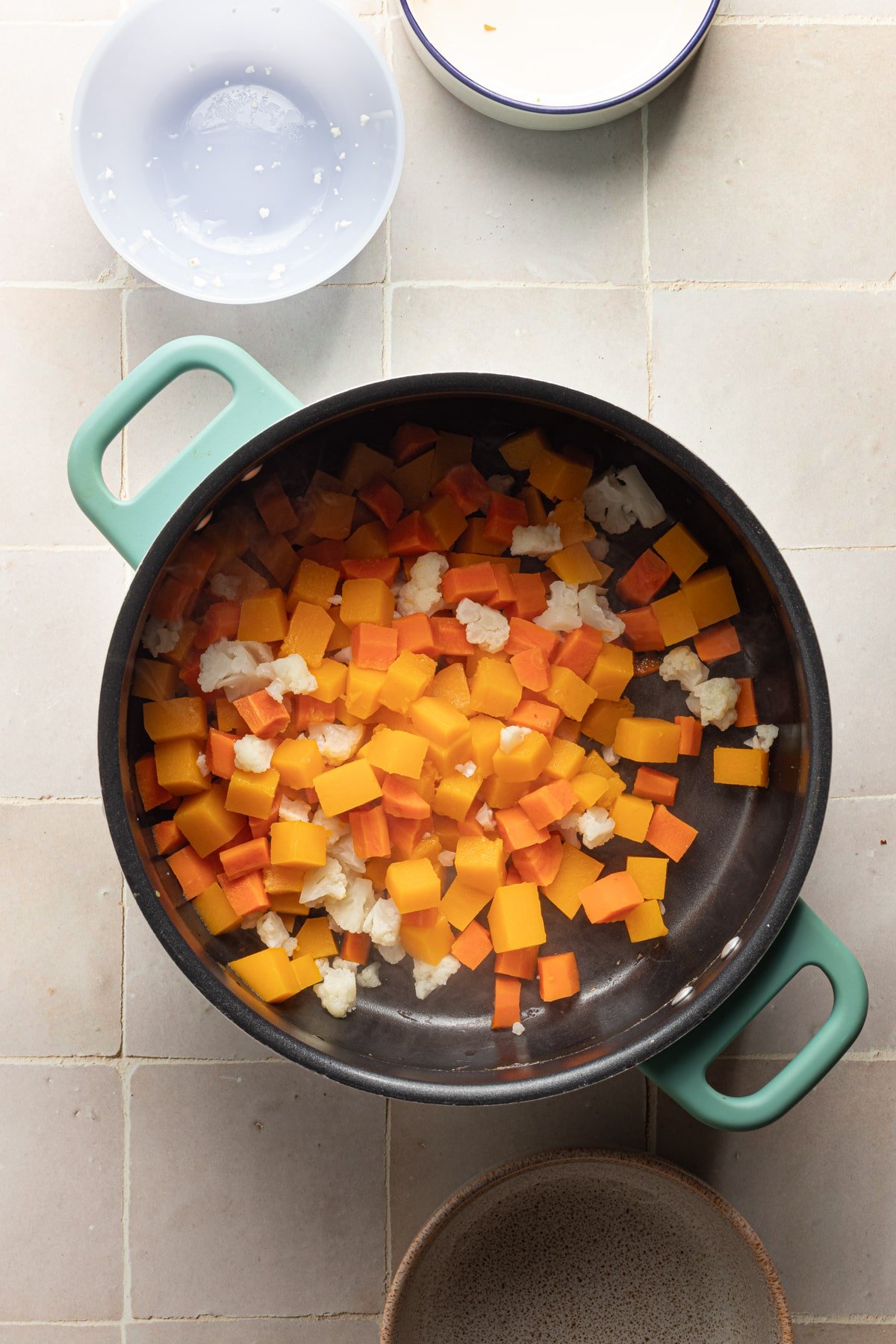 Butternut squash, cauliflower and carrots being cooked in a pot with water.