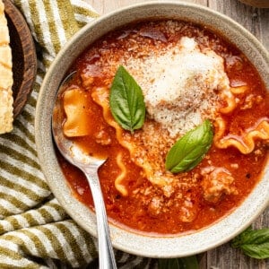 High protein lasagna soup in a bowl garnished with cheese topping and fresh basil.
