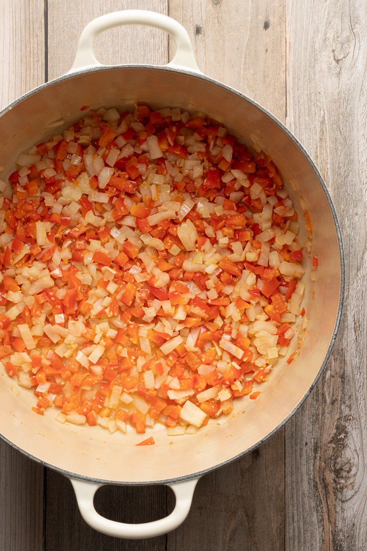 A large dutch oven with sautéed onions, peppers and garlic. 