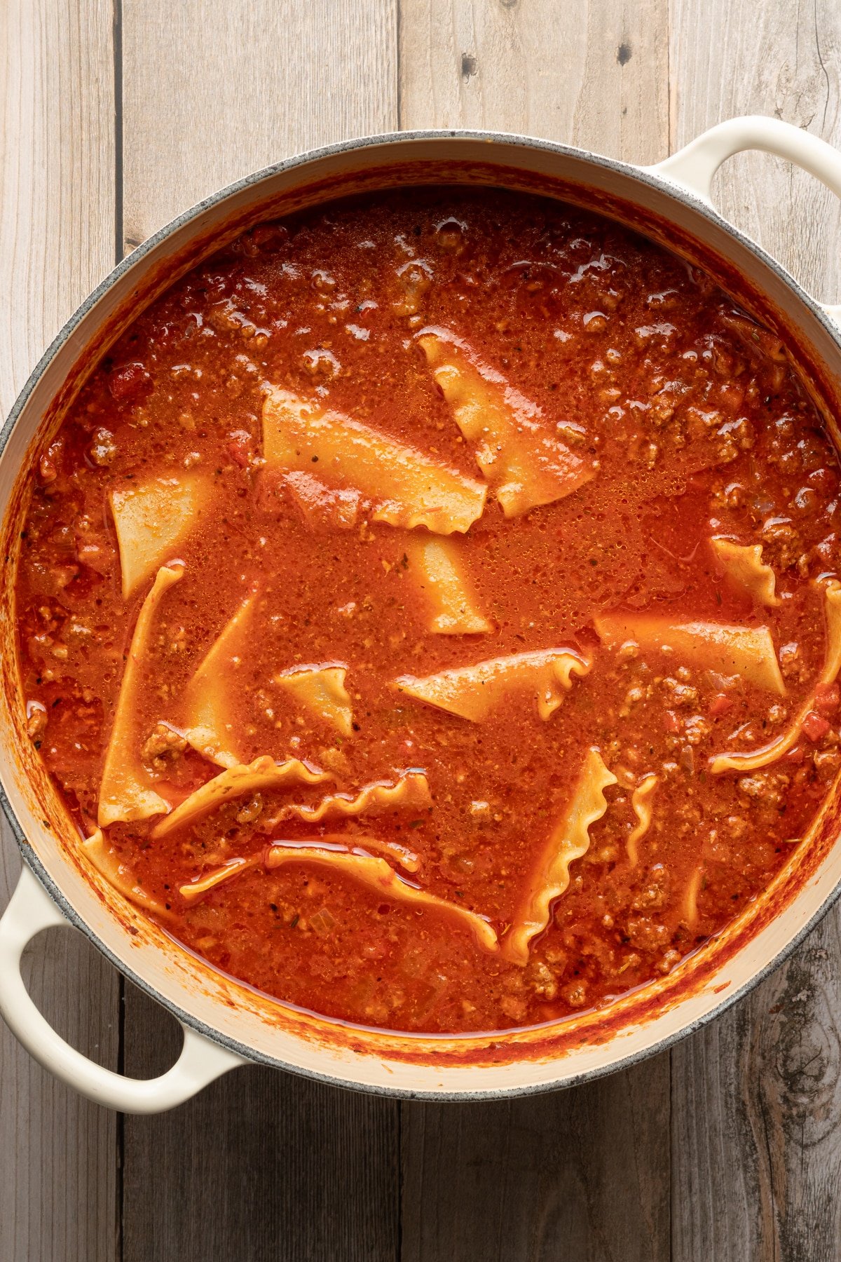 High protein lasagna soup in a dutch oven with broth, canned crushed tomatoes and broken up lasagna noodles.