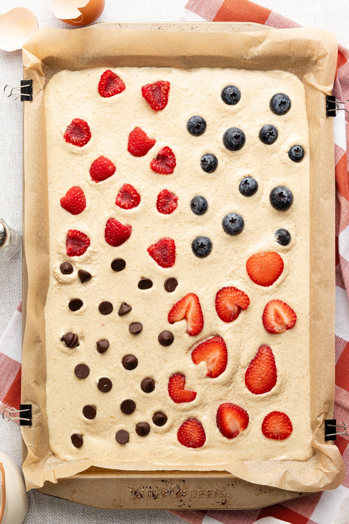 Protein pancake batter in a sheet pan topped with fruit and chocolate chips.