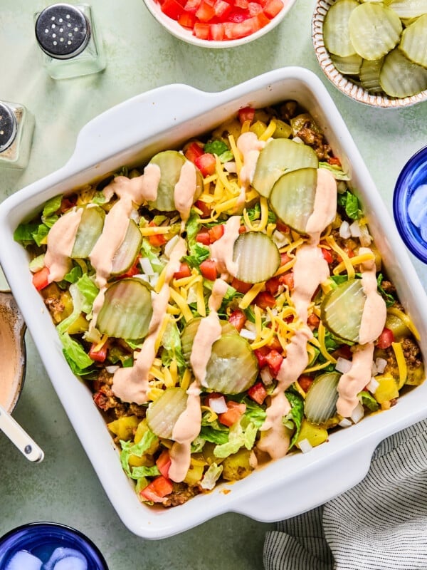 Big mac casserole topped with pickles, diced onion, tomatoes, cheese and a drizzle of sauce.