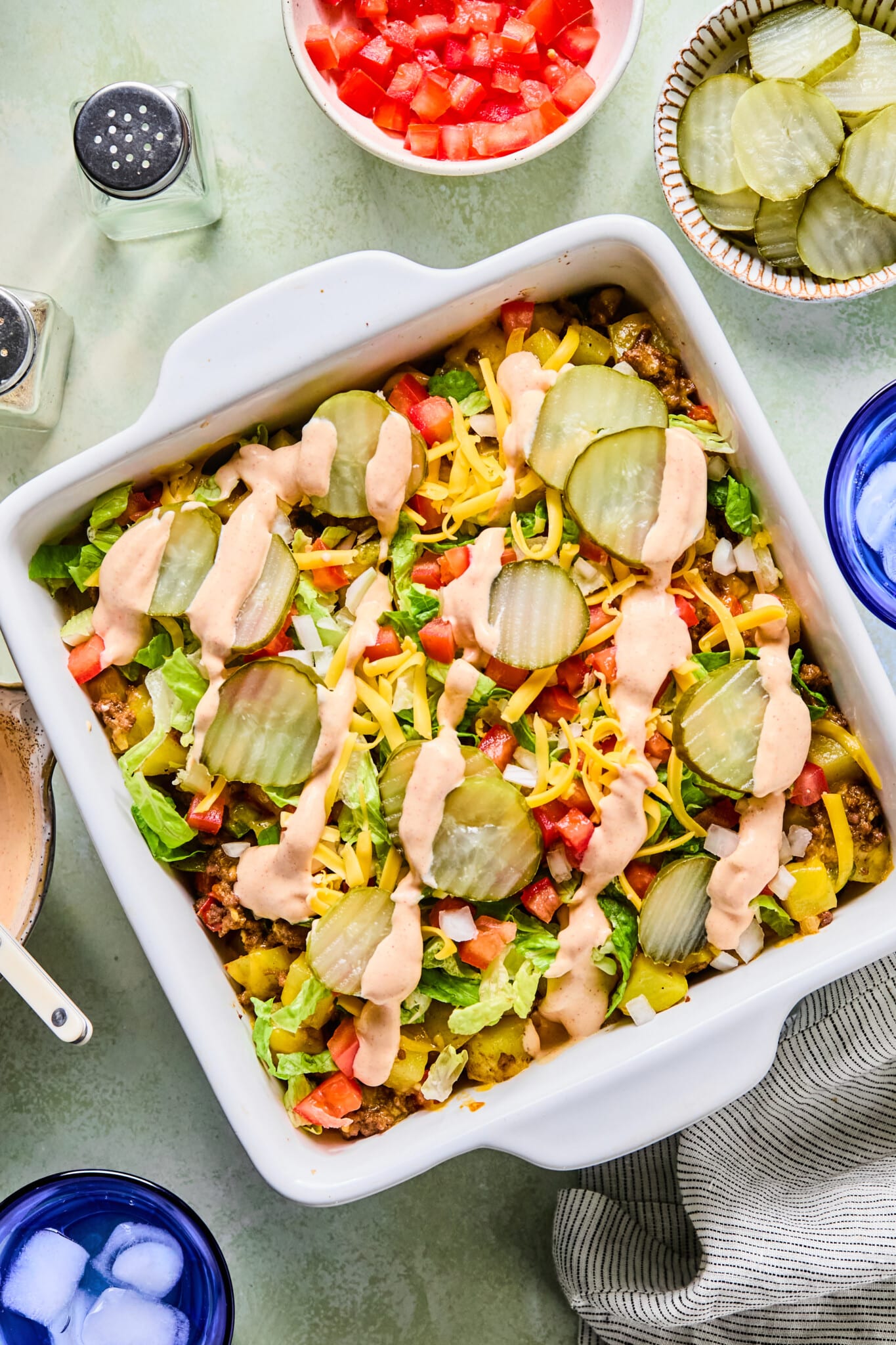 Big mac casserole topped with pickles, diced onion, tomatoes, cheese and a drizzle of sauce.