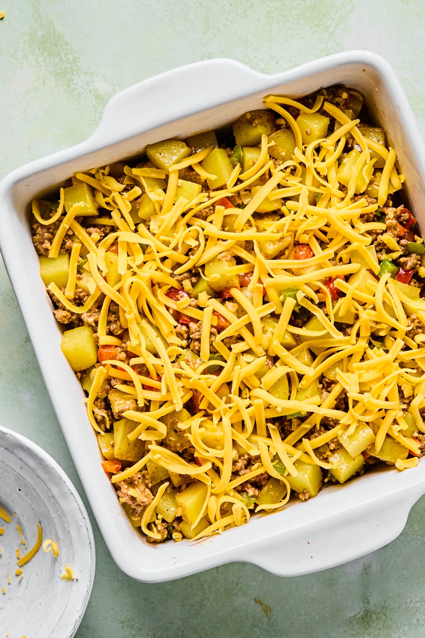 Big mac casserole in a baking dish topped with cheese.