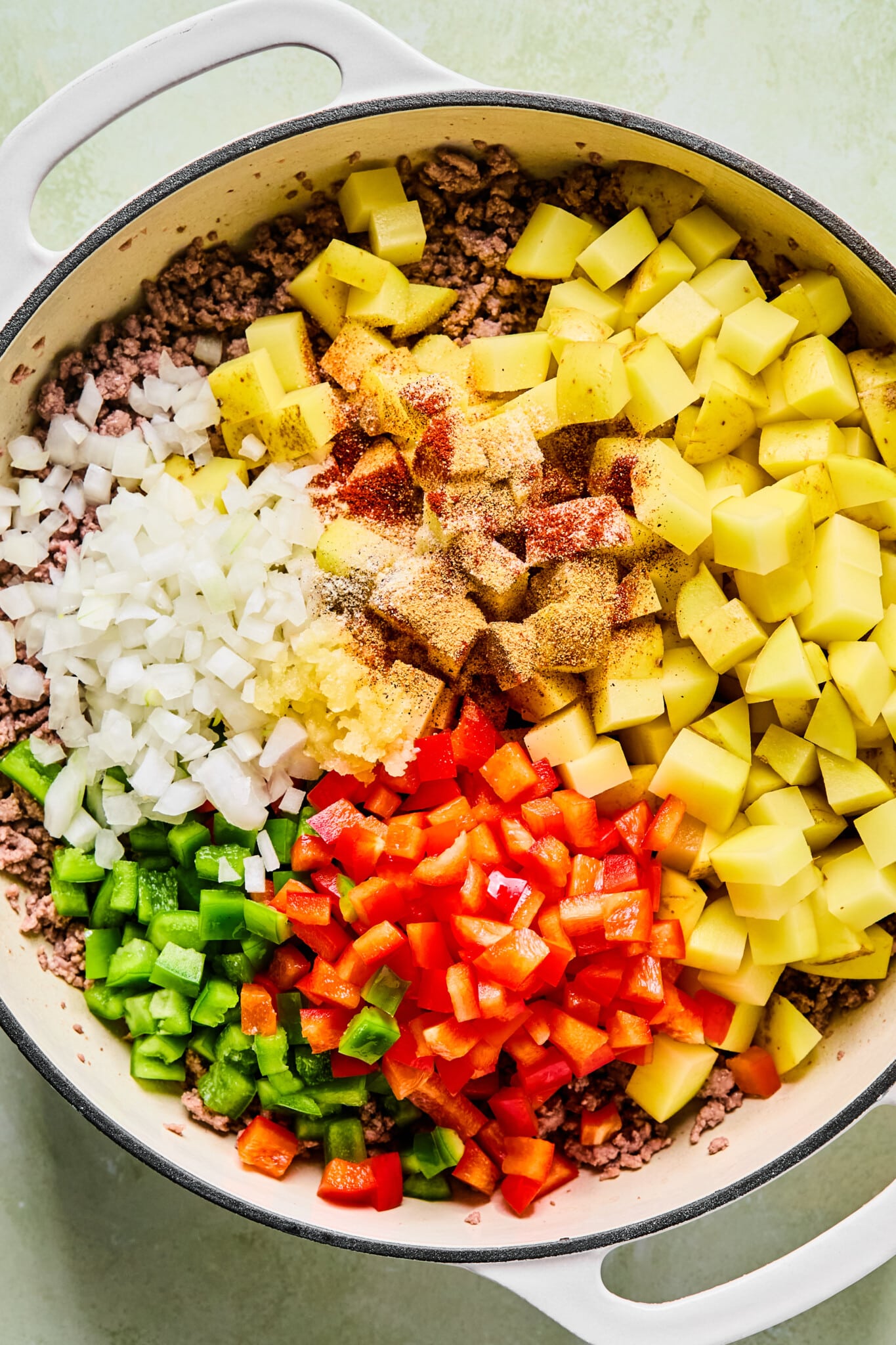 Ground beef, potatoes, peppers, onions and spices in a dutch oven.