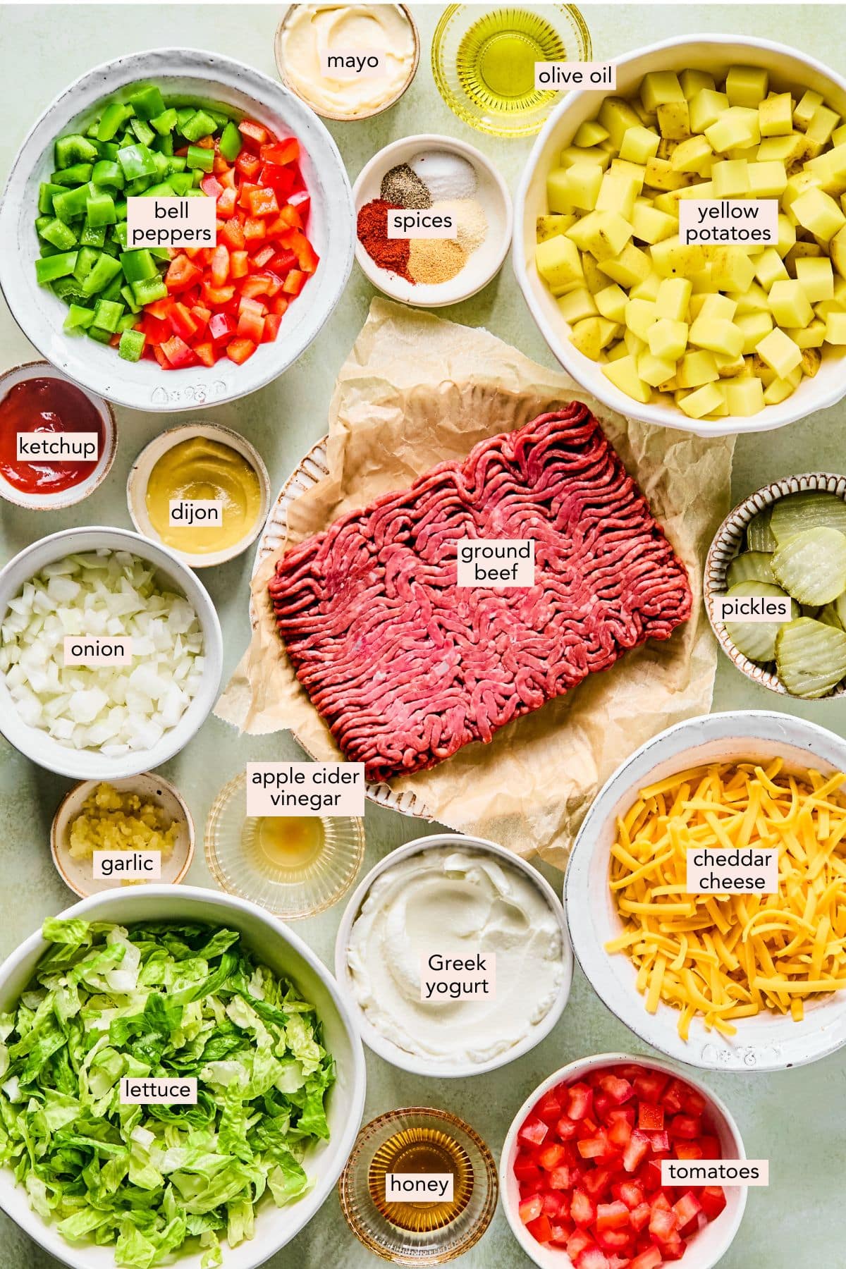 Ingredients for big mac casserole on a counter in individual bowls with labels.