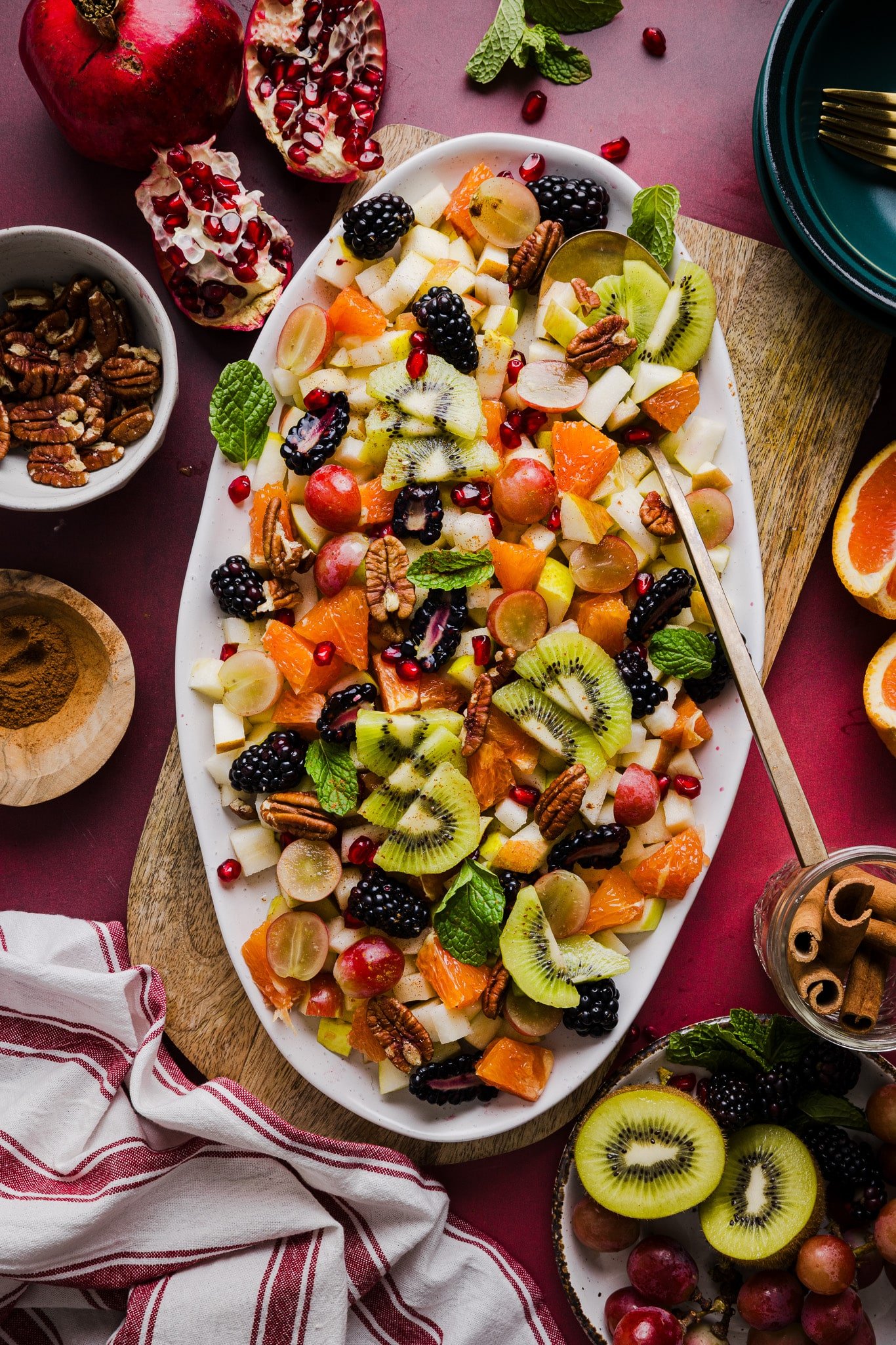 A festive and colorful thanksgiving fall fruit salad on a large white platter garnished with mint.