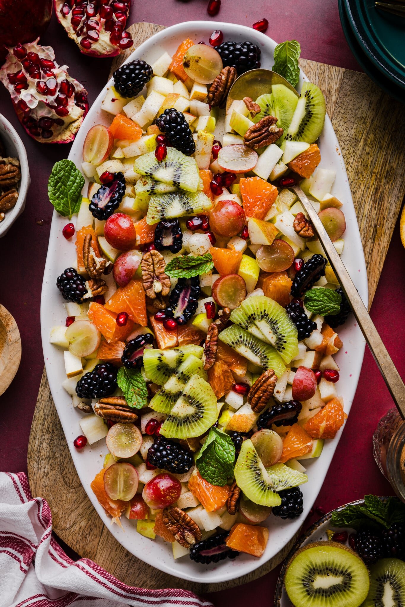 A festive and colorful thanksgiving fall fruit salad on a large white platter garnished with mint.