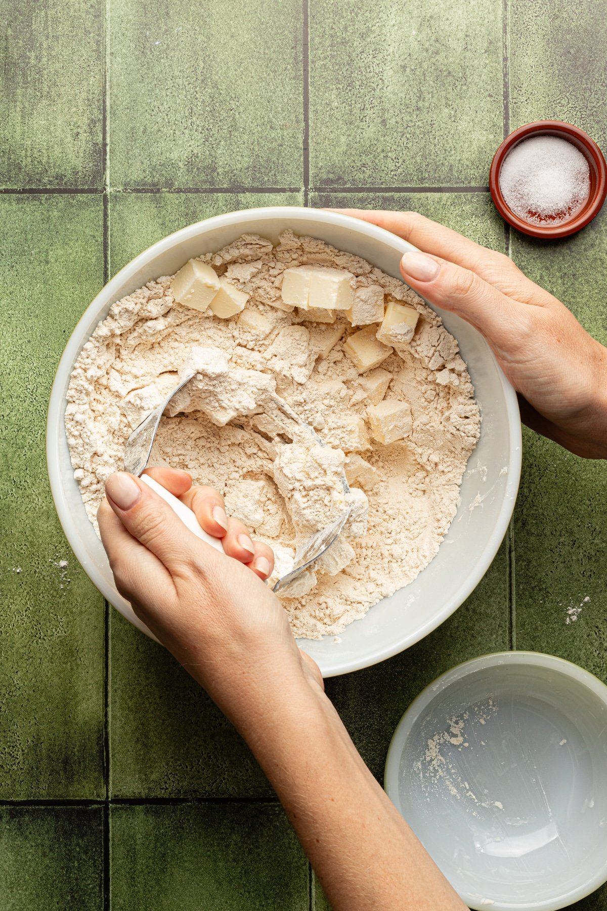 Whole wheat pastry flour and salt with butter being mixed in with a pastry cutter.