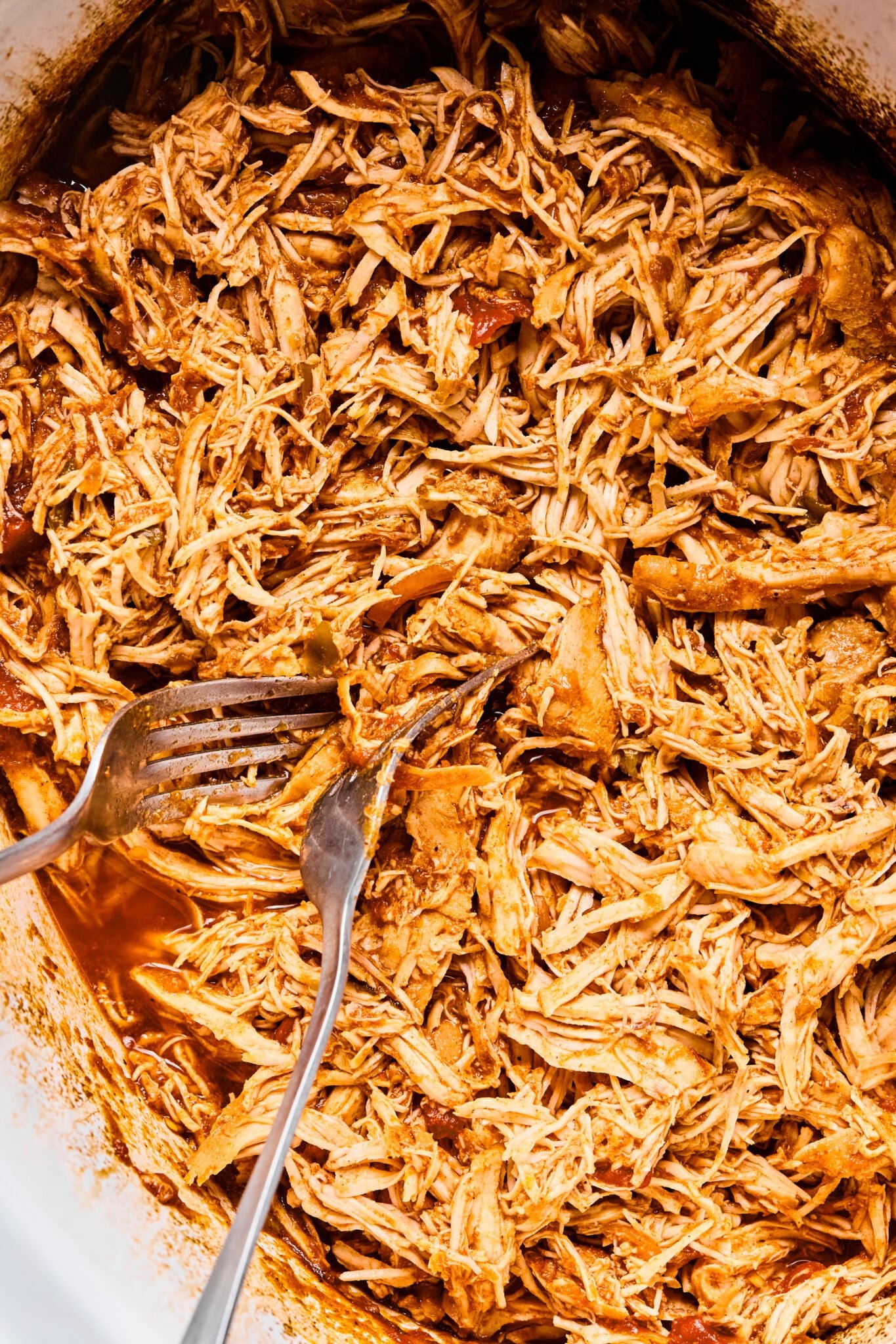 Shredded chicken for slow cooker shredded chicken tacos in a crock pot with two forks.