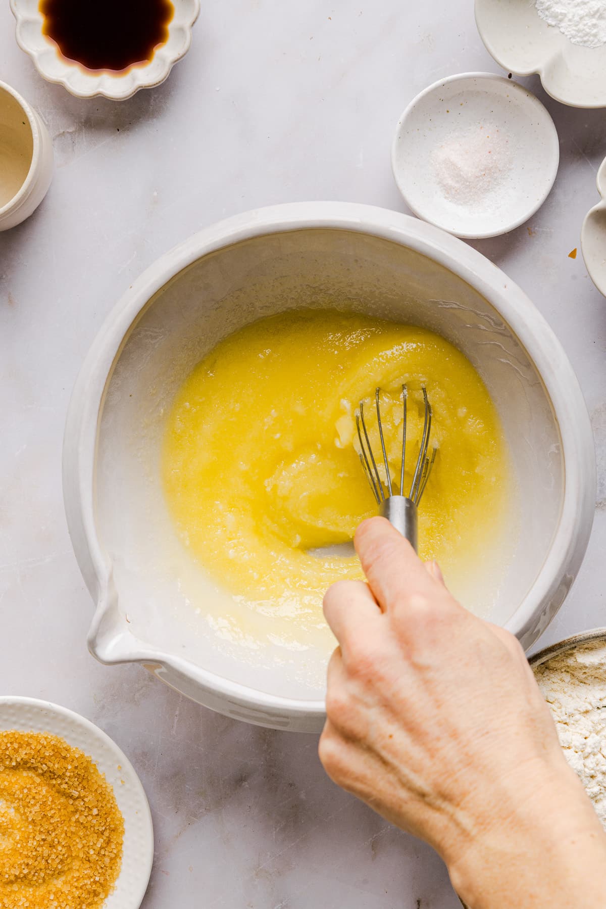 Butter, sugar, egg, vanilla & almond extract being whisked in a mixing bowl for whole wheat sugar cookies.