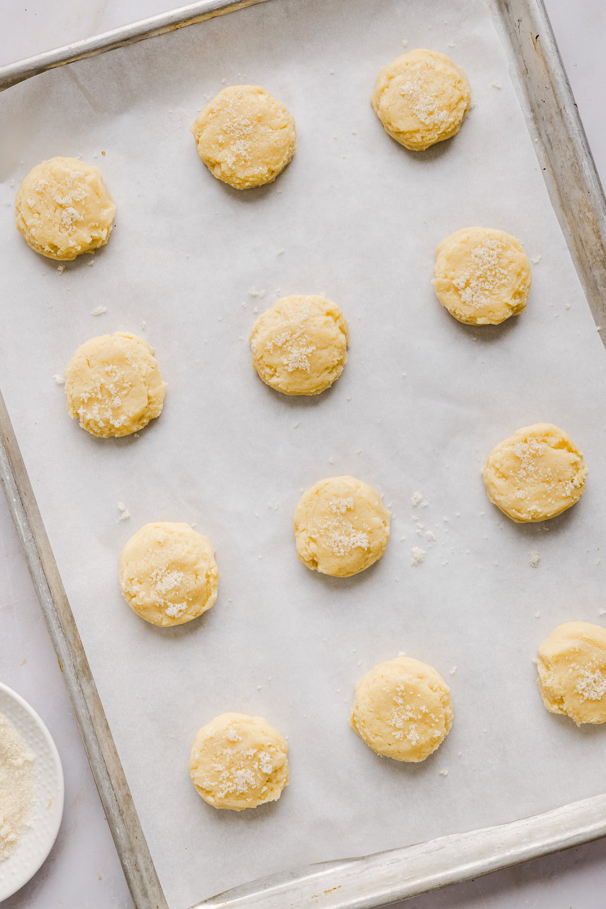 Whole wheat sugar cookie dough balls on a parchment lined baking sheet.