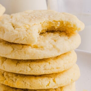 Five whole wheat sugar cookies stacked on top of each other with a bite taken out of the top cookie.