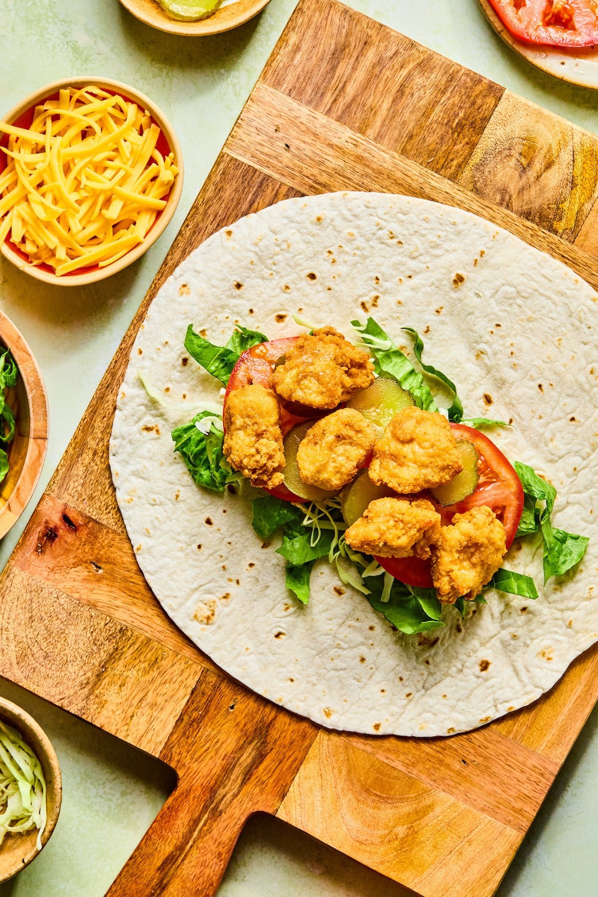 A chicken nugget being assembled on a wrap.
