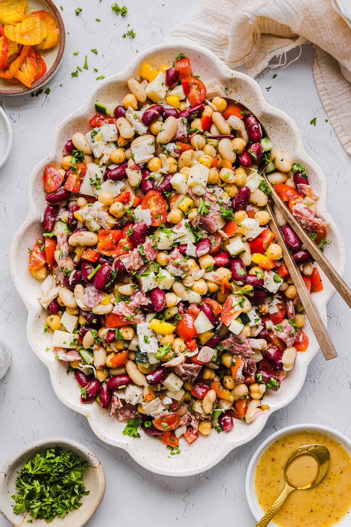 Grinder dense bean salad on a large platter with two serving spoons.