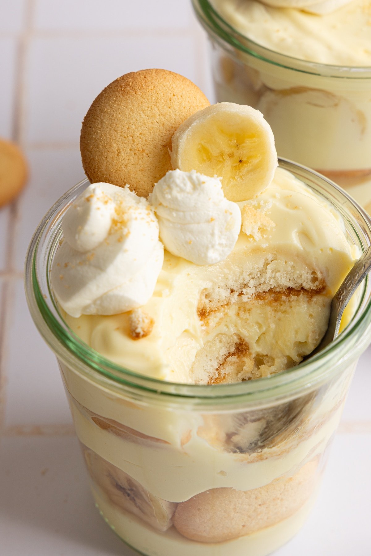 A scooped out shot of high protein banana pudding layered in a jar with whipped cream.