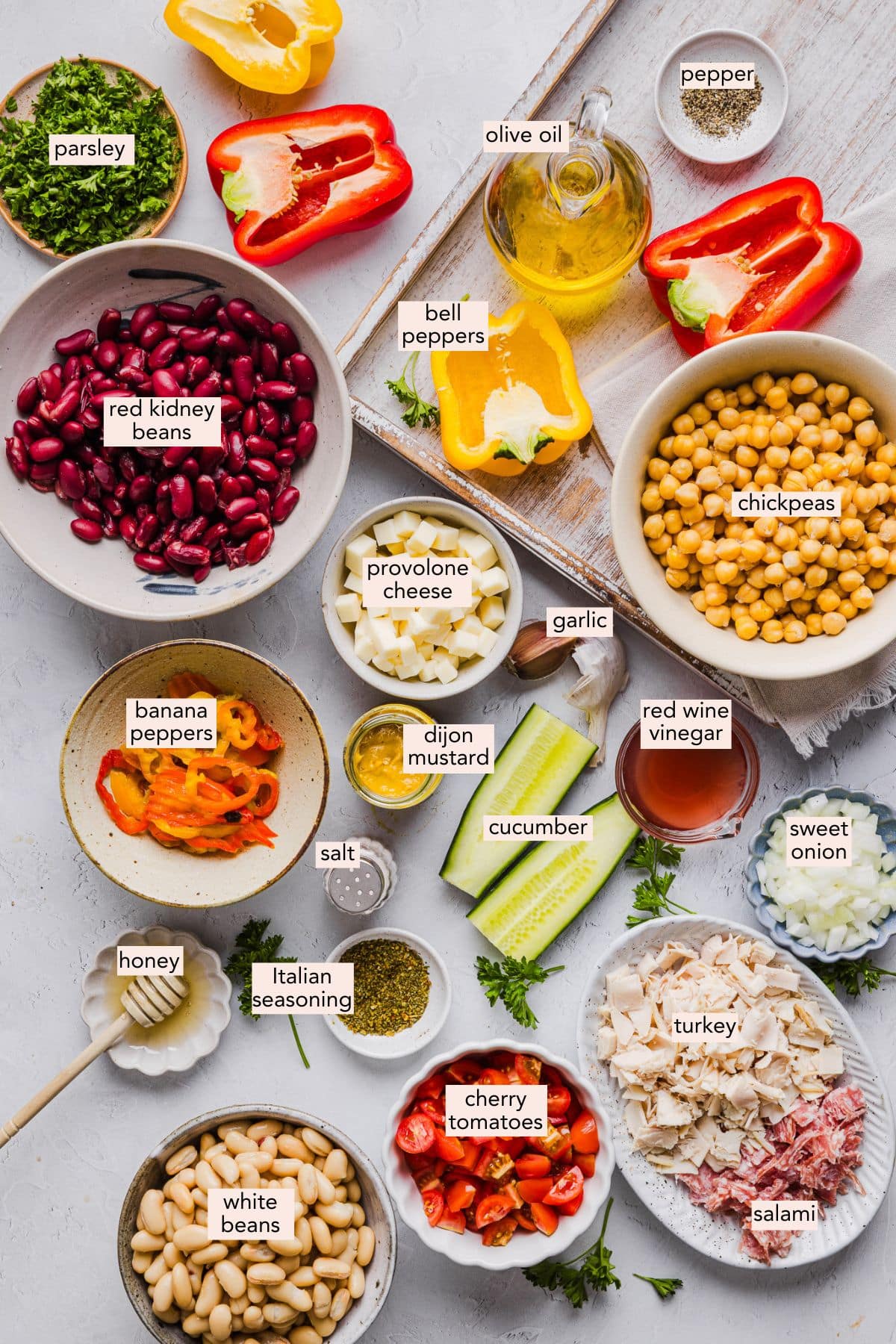 Italian grinder dense bean salad ingredients on a countertop with labels.