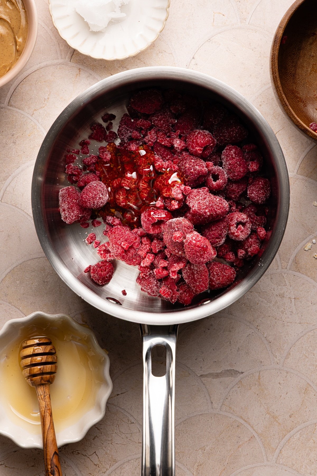 Frozen raspberries and honey in a small saucepan.