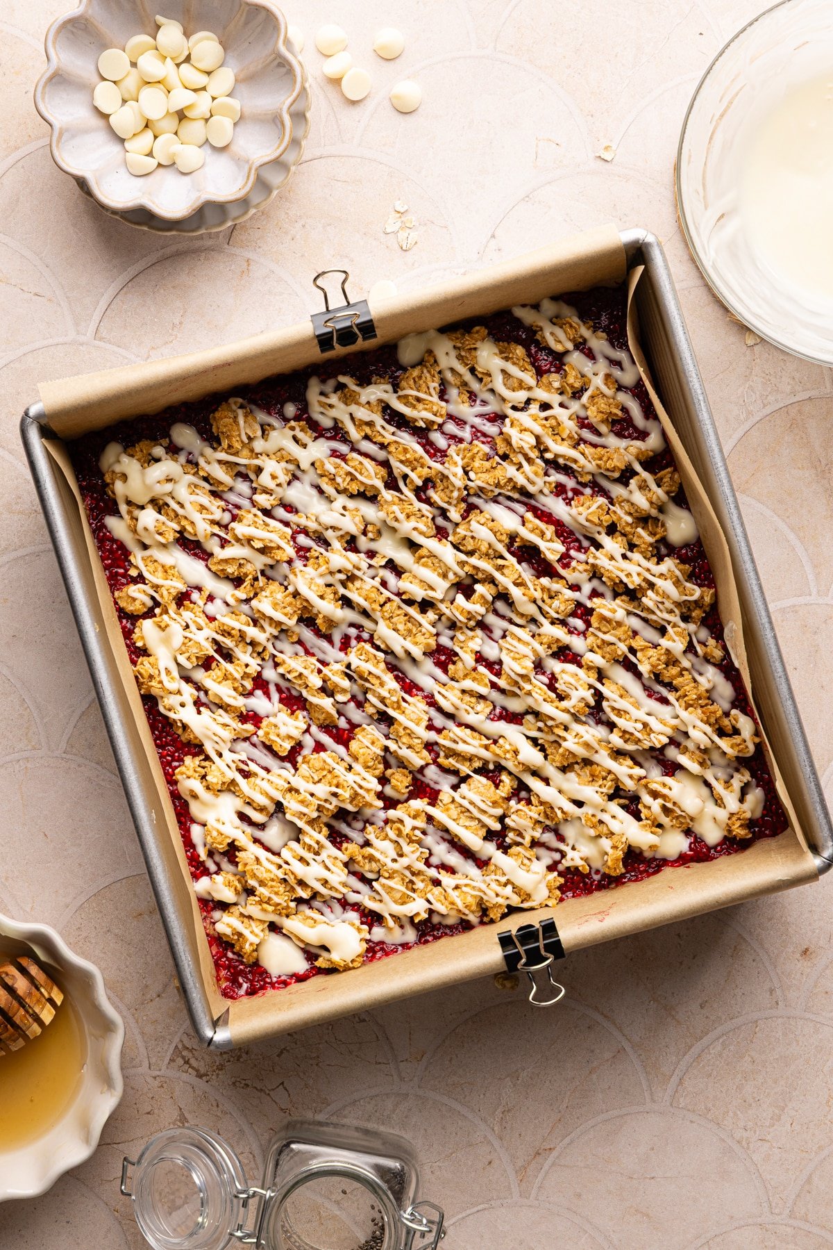 Assembled no bake PB and J oat bars in a square pan drizzled with white chocolate.