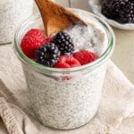 A small wooden spoon scoops some kefir chia pudding out of a glass container.