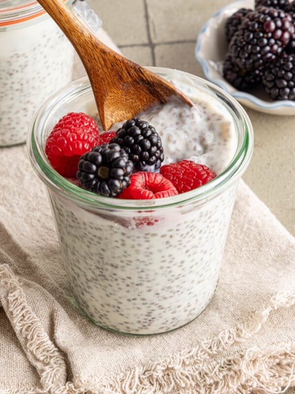 A small wooden spoon scoops some kefir chia pudding out of a glass container.