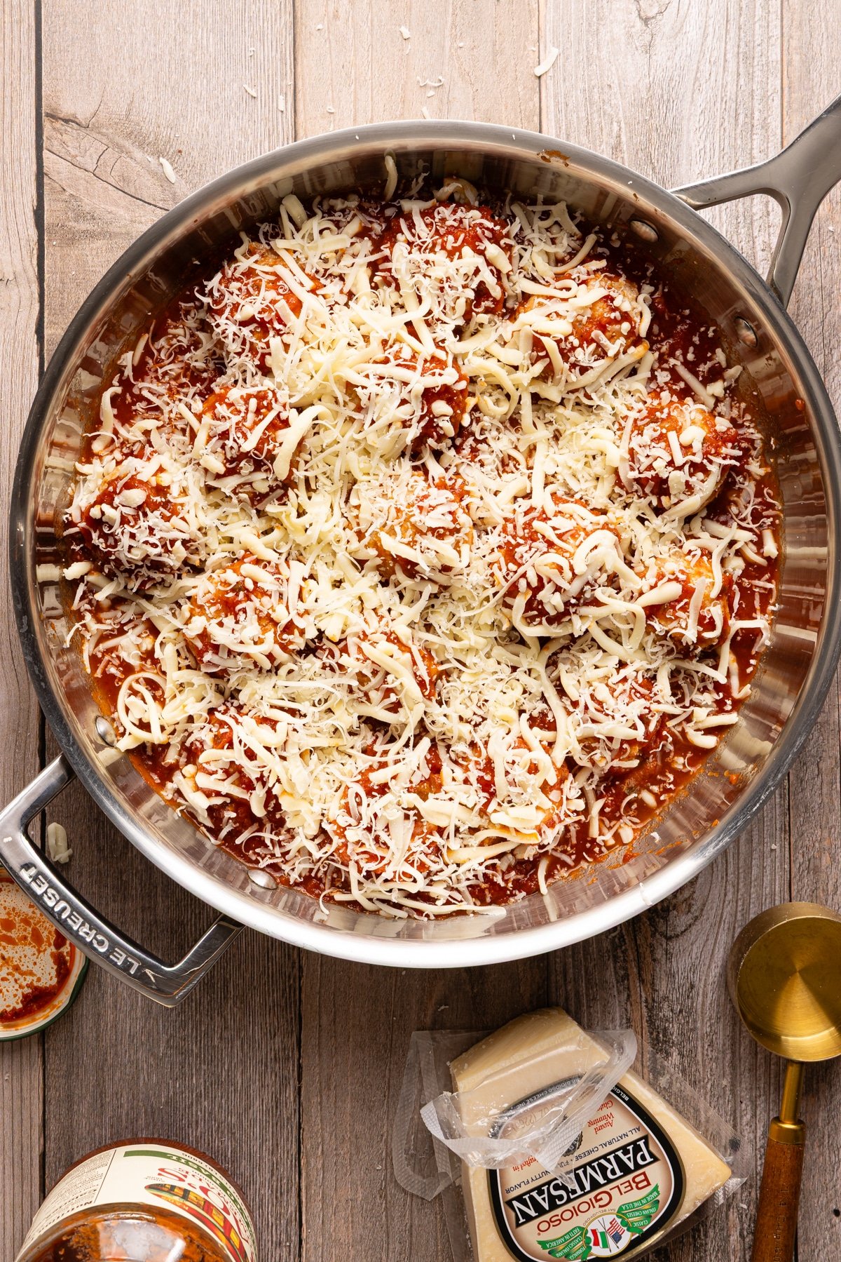 Chicken parm meatballs in a skillet with tomato sauce and topped with parmesan and mozzarella cheese.