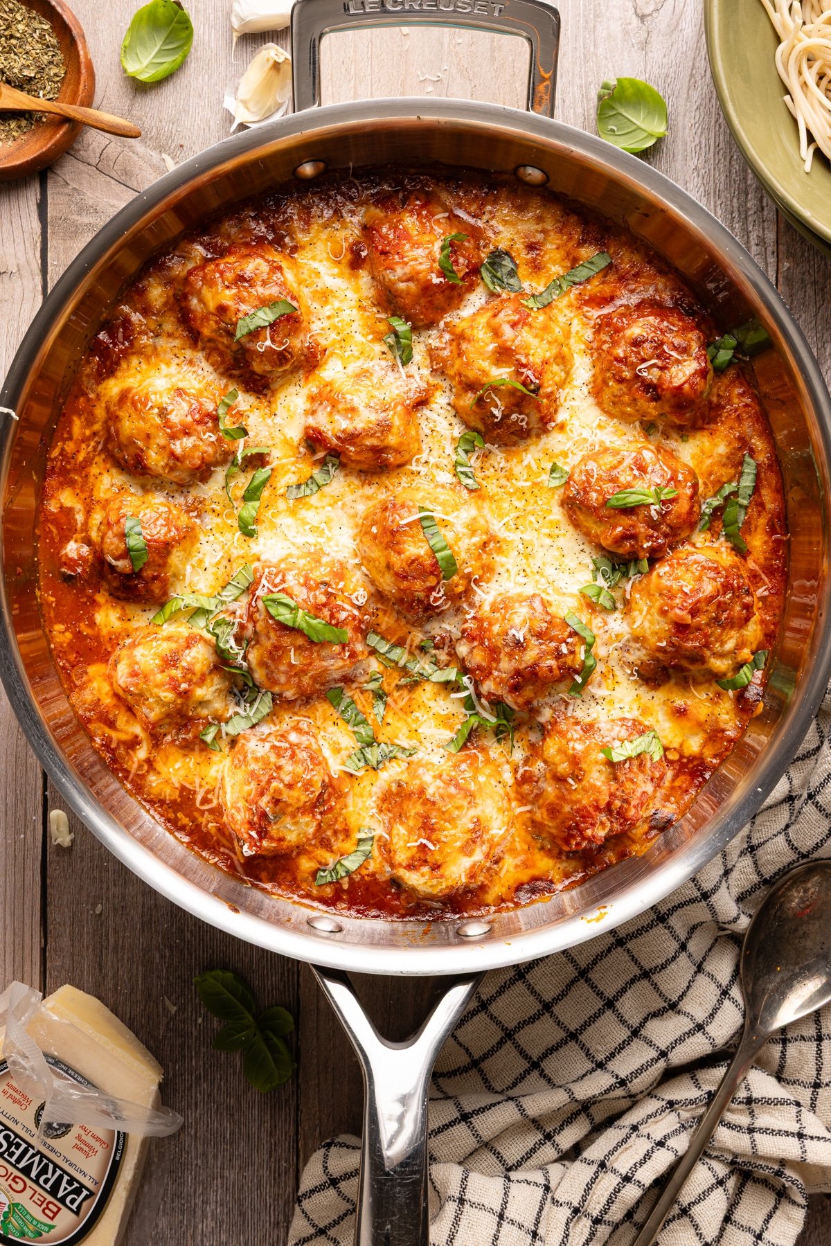 Chicken parm meatballs in a skillet topped with melted cheese and basil.