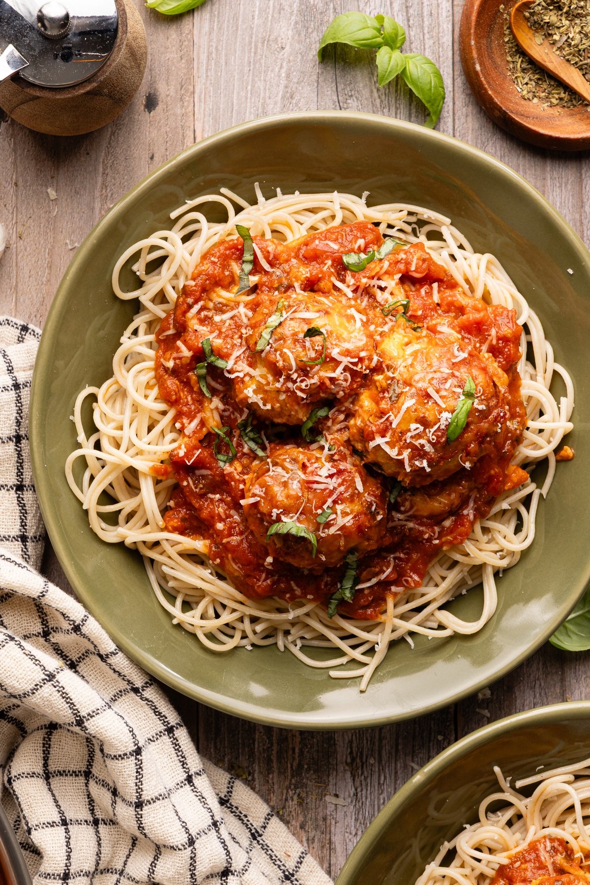 Chicken parm meatballs served on top of pasta and garnished with basil.