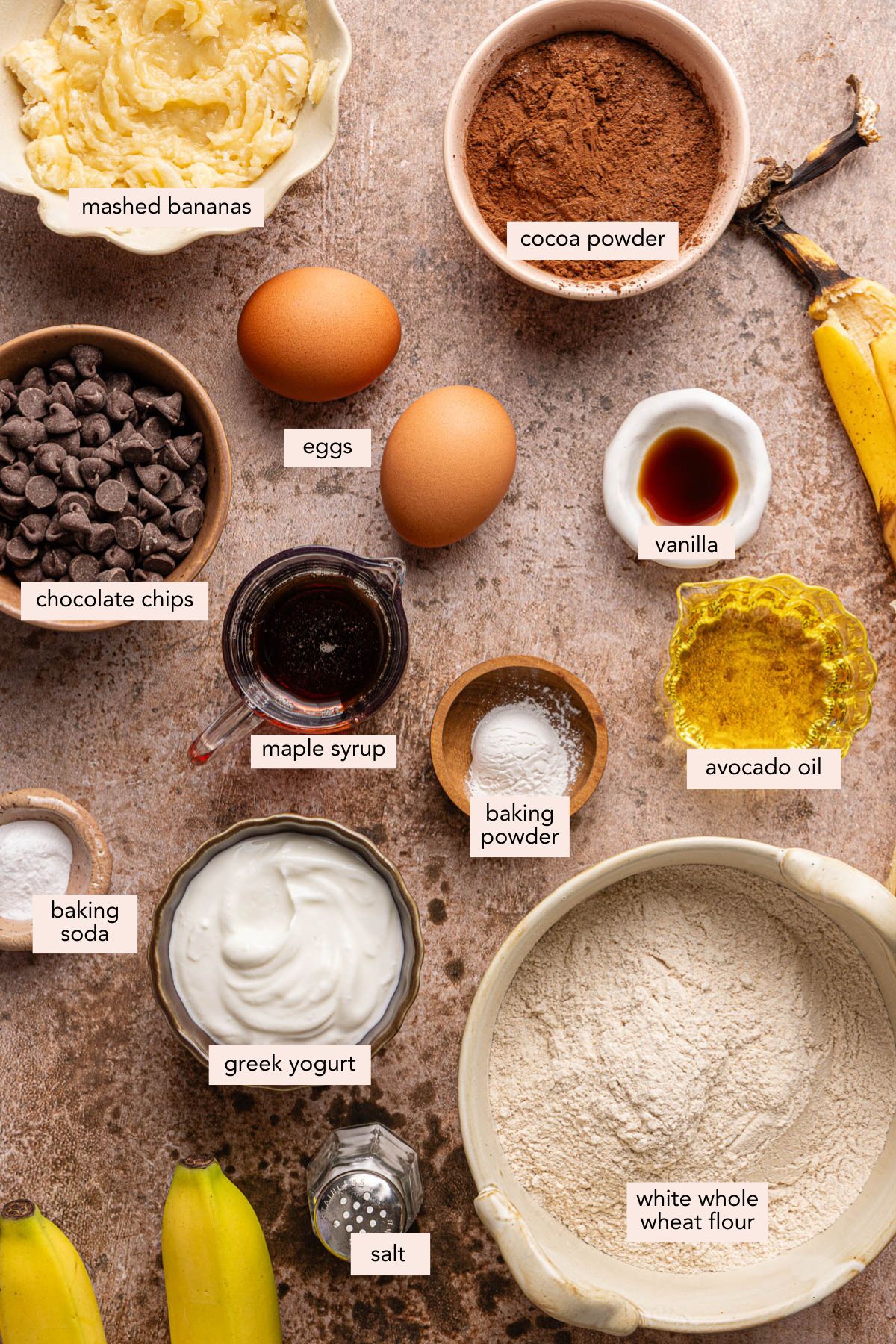 All of the ingredients for double chocolate banana bread in bowls on a countertop.