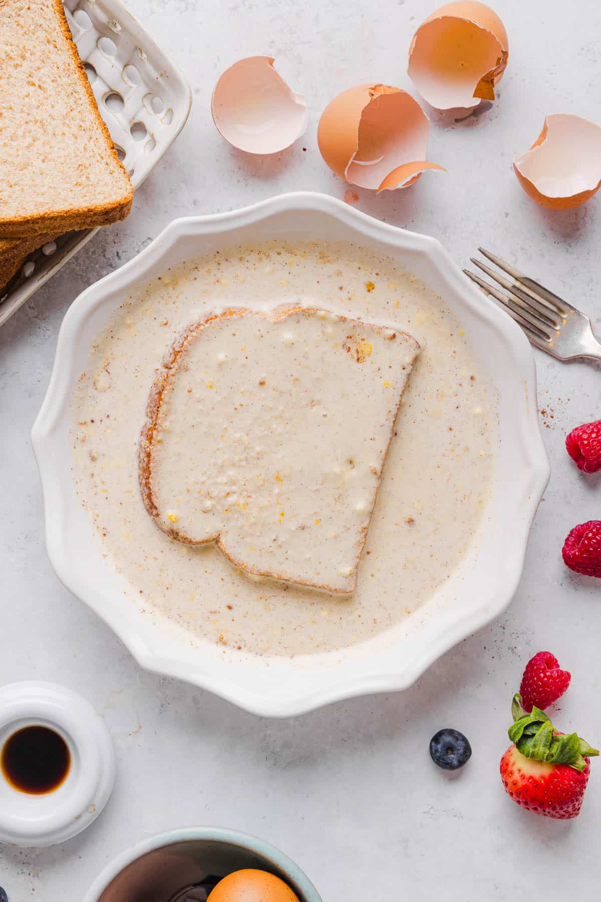 A piece of whole wheat bread dredged in the shallow baking dish with the french toast batter.